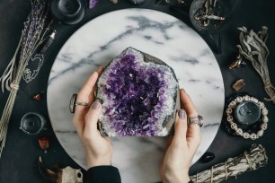 The witch is holding amethyst stone surrounded magic things. View from above.