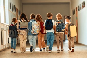 A group of schoolchildren with backpacks walking along a school corridor