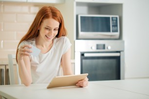 A woman uses her tablet and credit card to shop online.