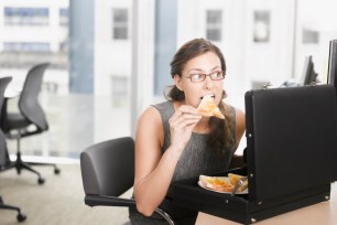 Businesswoman eating a slice of pizza from her briefcase