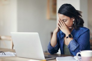 Shot of a young woman looking stressed while using a laptop to work from home